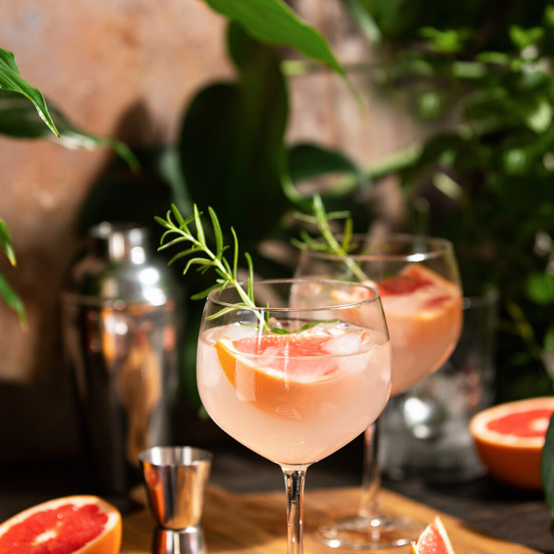 Pink grapefruit and rosemary gin cocktail  served in prepared gin cocktail glass on a tropical beach bar